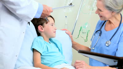 stock-footage-male-doctor-with-nurse-diagnosing-a-young-boy-patient-in-family-surgery