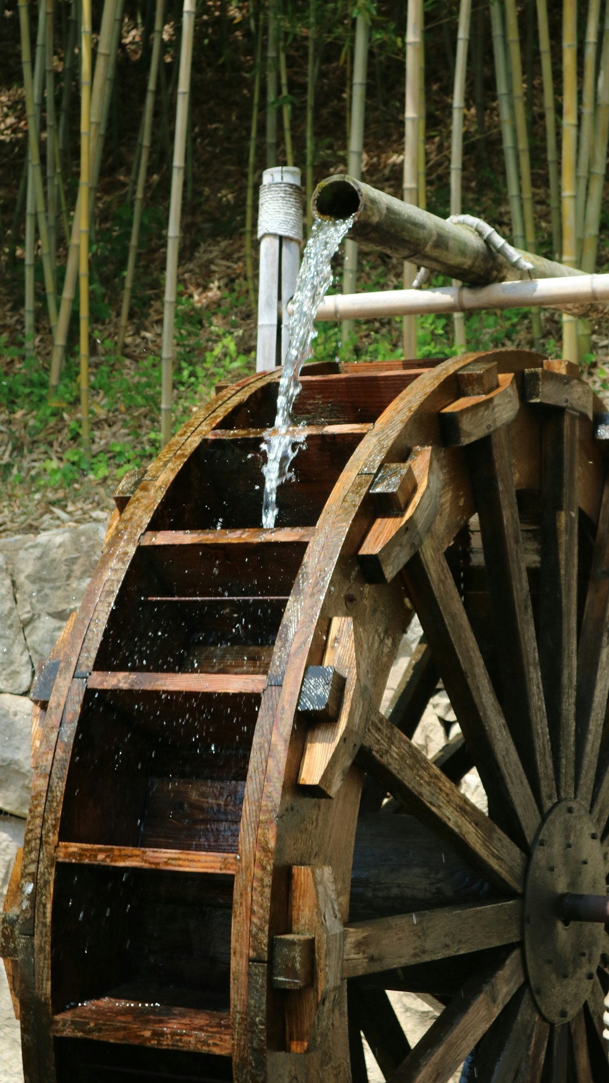 A wooden water wheel turning in a stream